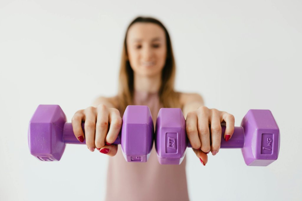 Female Doing Bicep Exercise With Dumbbells During Functional Training In Light Studio